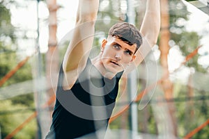 Muscular young man posing outdoors at sportsground in the park, preparing for workout training. Confident young fitness man ready