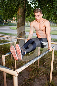 Muscular young man pull ups the horizontal bar. Street workout