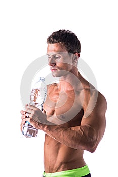 Muscular young man shirtless, drinking water from bottle