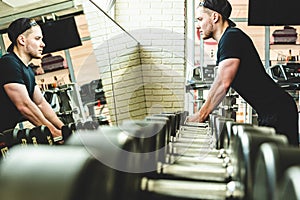 Muscular young man is training in the gym in front of the mirror