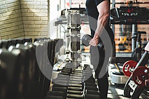 Muscular young man is training in the gym in front of the mirror