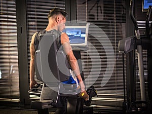 Muscular young man, training legs on gym machine