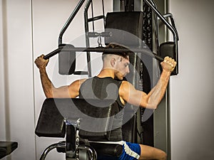 Muscular young man, training pecs on gym machine
