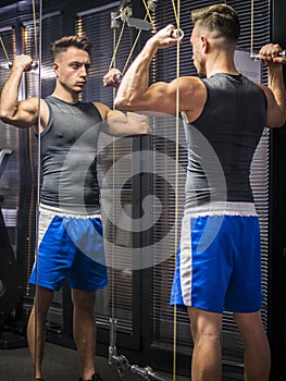 Muscular young man, training shoulders on gym machine