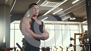 Muscular young man warming up in front of a mirror in workout room