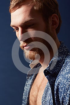 Profile of a man. A muscular young man wearing an open shirt and looking away.