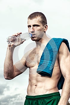 Muscular young man after a workout drinking bottle of water