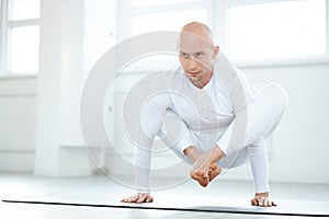 muscular young yogi man doing Urdhva Kukkutasana Upward Cock posture
