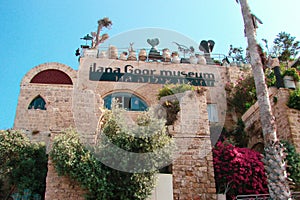 The museum building with a facade made of white large stones and a lot of plants around.