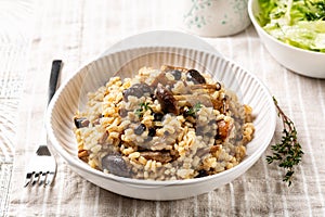 Mushroom barley risotto or orzotto in a white plate on a line tablecloth.