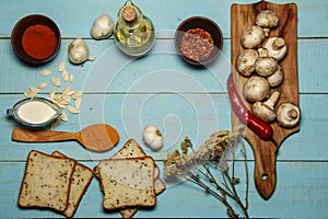 Mushroom champignons, garlic, pepper, cardamom, sour cream sauce, olive oil, bread on a wooden beautiful background. View from abo