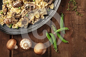 Mushroom and cheese pasta. Farfalle with cremini and green peas close-up