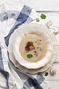 Mushroom cream soup with rye croutons on a white wooden table. Top view, flat lay