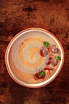 Mushroom cream soup, shot from above on a dark rustic wooden table
