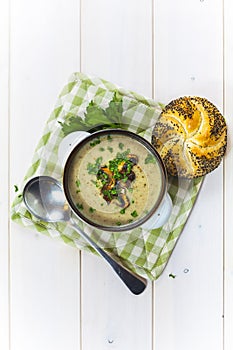 Mushroom soup with a bread roll and parsley