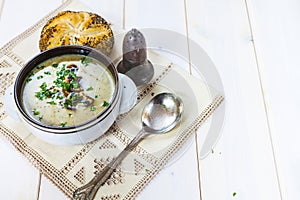 Mushroom soup with a bread roll and parsley