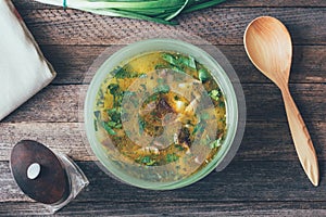 Mushroom soup in the dish, the green onions, the wooden spoon, and a pepper mill on the old wooden table