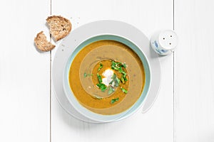 Mushroom soup garnished with fresh parsley on white table