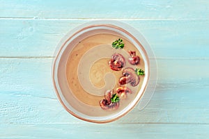 Mushroom soup, garnished with parsley, shot from above on a wooden background