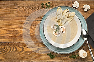 Mushroom soup with parsley on rustic wooden table