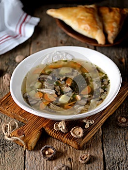 Mushroom soup with potatoes, carrots, onions and chicken meat on an old wooden background. Rustic style.