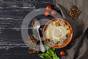 Mushroom soup puree. A cup of mushroom soup with rusks on a rustic background with a napkin and a spoon.