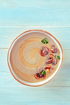 Mushroom soup in a rustic bowl, overhead shot on a teal wooden table