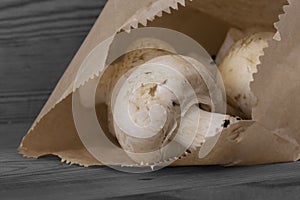 Mushrooms with a brown paper bag on a wooden background.  Environmentally friendly recycling packaging