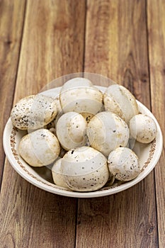 Mushrooms in a ceramic plate on a wooden floor. Close up