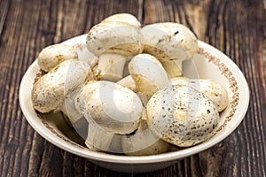 Mushrooms in a ceramic plate on a wooden floor. Close up