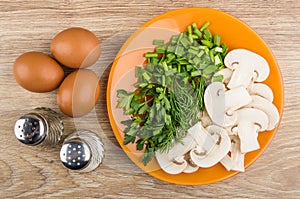 Mushrooms, greens in plate, eggs, salt and pepper on table