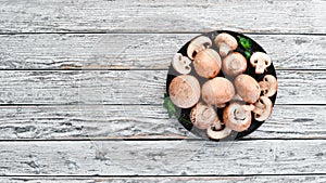 Mushrooms in a plate. Champignons on the old background. Top view.