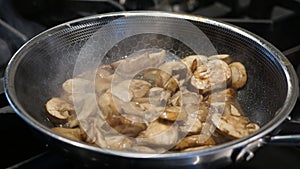 Mushrooms sautaing on the stove in a small pan.