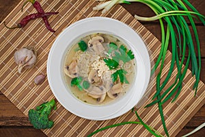 Mushrooms soup with greens, garlic and parmesan cheese. Rustic style. Wooden rustic background. Top view