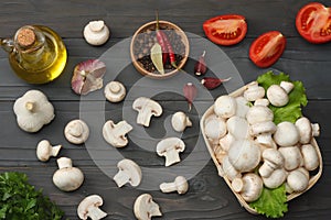 mushrooms with tomatoes, parsley, oil, garlic, chili pepper, peppercorns on dark wooden background. top view