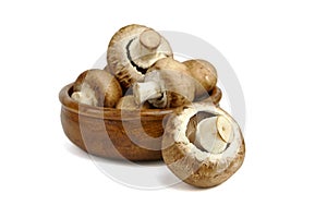 Mushrooms in wooden bowl isolated on white background. Whole fresh brown champignons