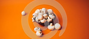 Mushrooms in a wooden bowl on an orange background. The small white champignon in a plate and scattered near it.