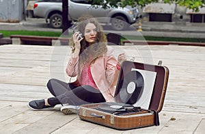 Music addicted girl having fun with headphones and a portable stereo vinyl record system