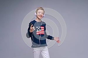 Music app. Cute kid using phone with headphones, listening to great song