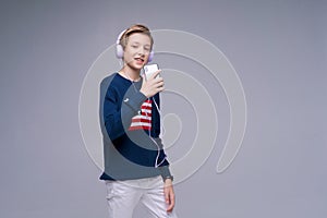 Music app. Cute kid using phone with headphones, listening to great song