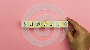 Music and  art entertainment instruments background concept.Close up Asian young man holding musical note icon on cube blocks