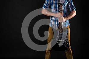 Music and art. The guitarist holds the electric guitar with his hands, on a black isolated background. Playing guitar. Horizontal