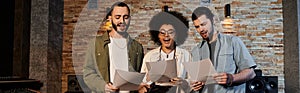 A music band rehearses, holding papers photo