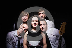 music band in studio.Musicians and woman soloist posing over black background