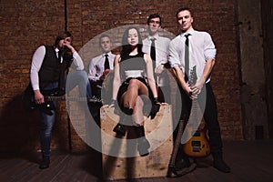music band in studio.Musicians and woman soloist posing over brick wall