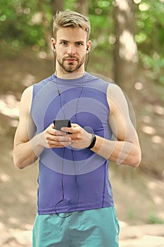 Music best companion to run. Man athlete on busy face set up play list, nature background. Sportsman training headphones