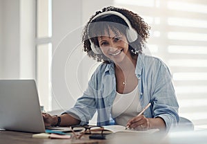 Music boosts my productivity. an attractive young woman sitting alone in her home and writing in a notebook while