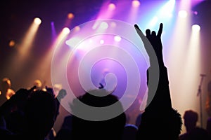 Music brings us together. A crowd of people watching a band play on stage at a nightclub.