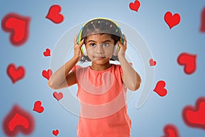 Music, childhood and technology concept- little indian girl with headphones over blue color backgroundound with red hearts