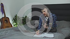 Music composer creating lyric music. Young man in headphones learning new chords on electric guitar. Musician plays on guitar on b